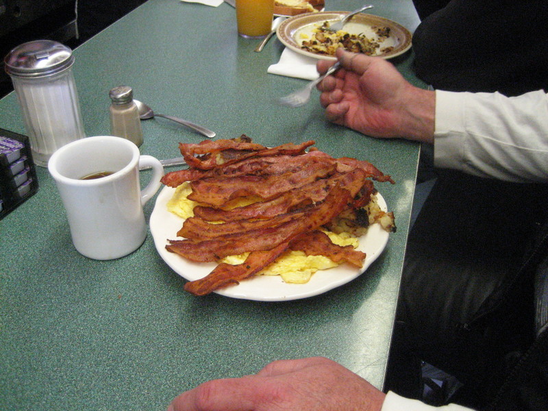 "a couple scrambled eggs and bacon"